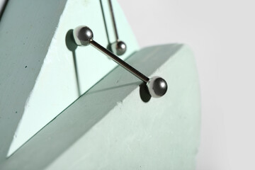 Plaster podiums with silver barbells for piercing on grey background, closeup