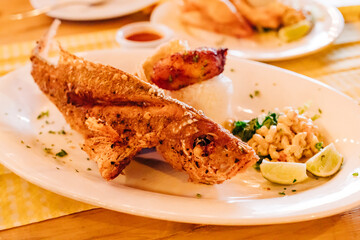 Deliciously prepared whole fried fish served with lime, rice, and side dishes at a tropical restaurant setting