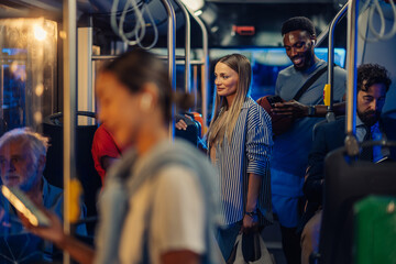 Passengers using smartphones and riding on a bus at night