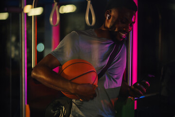 Young basketball player using smartphone on the bus at night