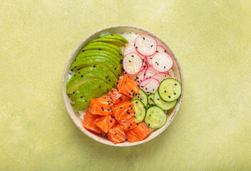 Poke bowl, a traditional hawaiian dish with diced raw salmon, avocado, vegetables served with rice and vegetables, a healthy meal on green background
