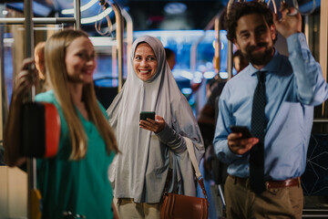 Multi ethnic commuters using smartphones on a bus or tram