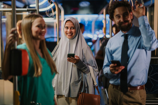 Multi ethnic commuters using smartphones on a bus or tram - Powered by Adobe