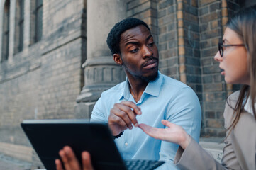 Business colleagues discussing work using tablet outside office building