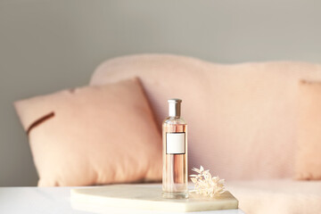 Bottle of perfume and beautiful flowers on table at home