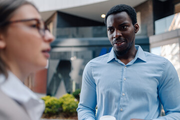 Business partners discussing during coffee break outside office building