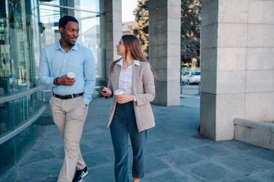 Businesspeople walking and talking outdoors during coffee break
