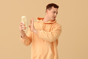 Young man refusing to eat doner kebab on beige background