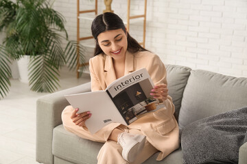 Beautiful young happy woman reading magazine at home