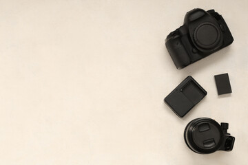 Professional photo camera, lens, charger and buttery on light background