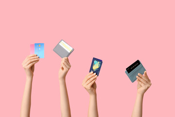 Female hands with credit cards on pink background