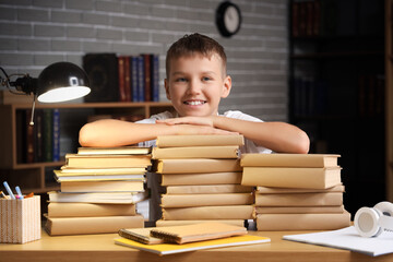 Teenage boy with stacks of books on table in library