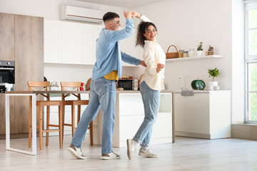 Obraz premium Happy young beautiful couple dancing in kitchen at home