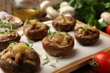 Delicious stuffed mushrooms with melted cheese and thyme on table, closeup
