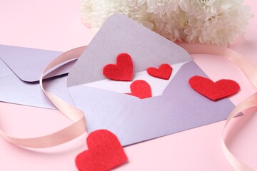 Love letters, red hearts, ribbon and flowers on pink background, closeup