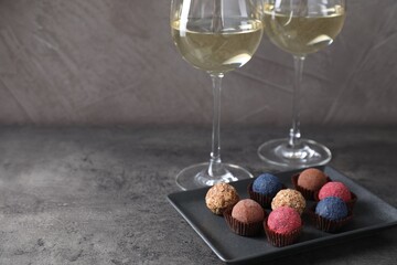 Tasty wine in glasses and truffle bonbons on grey table, closeup. Space for text