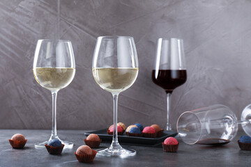 Tasty wine in glasses and truffle bonbons on grey table