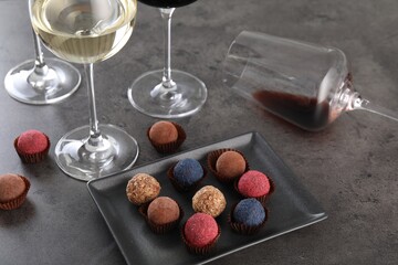 Tasty wine in glasses and truffle bonbons on grey table, above view