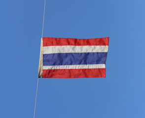 Thai national flag on empty blue sky background.