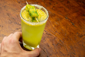 Creative frozen mango or lulo Margarita cocktail with a salt rim and a green ice pop (popsicle)...