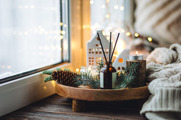 Natural Christmas essential oil, home aroma diffuser. Burning candles, branches of fir tree....
