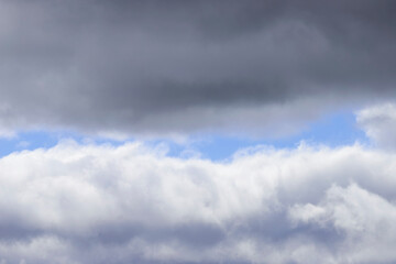 A dramatic sky featuring heavy, dark grey storm clouds in the upper and lower sections, contrasting...