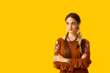Beautiful young woman in Indian costume on yellow background. Native American Heritage Month