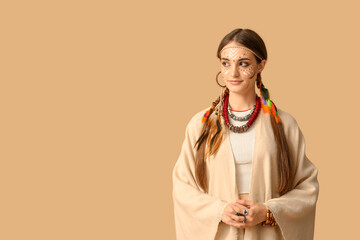 Beautiful young happy woman in Indian costume on beige background. Native American Heritage Month