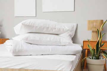 White pillows with folded blanket on bed in light room
