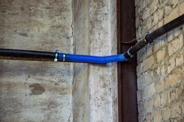 Plastic and metal pipes are connected along a textured wall, showcasing an industrial installation...