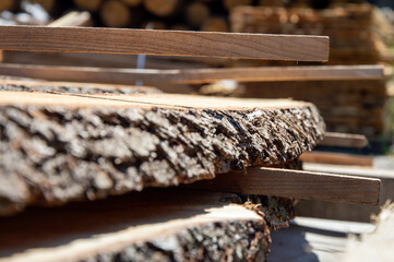Sunlight highlights freshly cut wood planks stacked at a lumberyard, showcasing natural textures...
