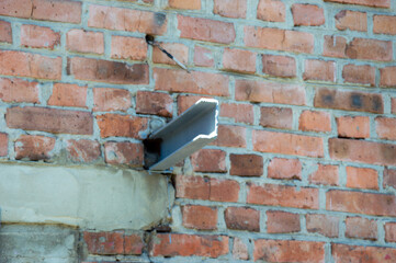 A metal pipe extends from a brick wall, revealing ongoing construction work and urban maintenance...
