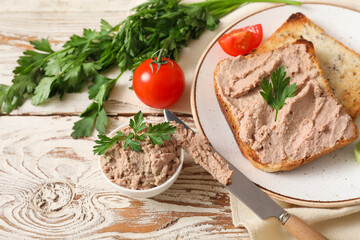 Plate with tasty pate, toasts, tomatoes and parsley on light wooden background