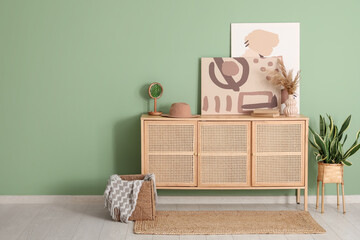Chest of drawers with decor, basket and picture near green wall in room