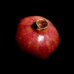 Artistic photograph of a whole pomegranate against a dark background. Dramatic low-key lighting...