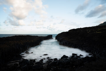 Fototapeta premium Ethereal still water in a rock channel with blue sky and sparse clouds, long exposure on Kauai, Hawaii