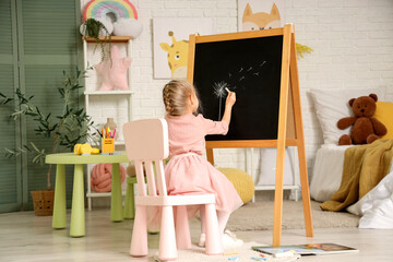 Cute little girl drawing blowball on chalkboard at home, back view