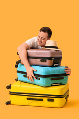 Young man with different suitcases and stylish hat on yellow background. Travel concept