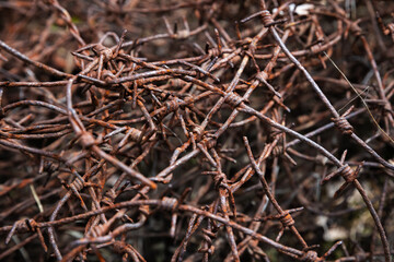 Rust-covered barbed wire tangled together, showcasing aged metal, sharp edges