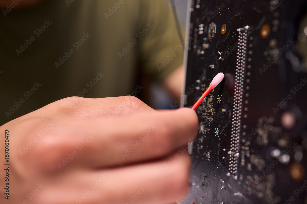 Poster a close up view of a hand engaged in the process of cleaning a circuit board component