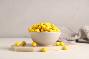 Bowl with cheese coated peanuts on light background