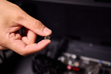 A Hand Holding a Small Electronic Component Close to a Computer Motherboard for Setup