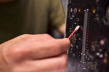 A Close Up View of a Hand Engaged in the Process of Cleaning a Circuit Board Component