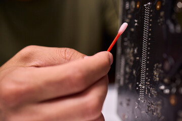 A Close Up View of a Hand Engaged in the Process of Cleaning a Circuit Board Component