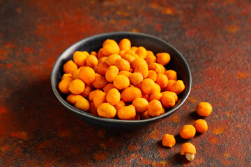 Bowl with chilli coated peanuts on red grunge table
