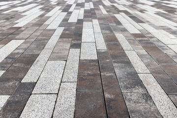 Urban paved outdoor surface displays a pattern of interlocking brickwork tiles