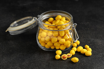 Jar with cheese coated peanuts on black background