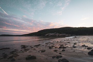 Low tide at sunset along a rocky beach in Acadia National Park, Maine. Soft pastel clouds and...