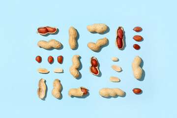 Unpeeled and peeled peanuts on blue background