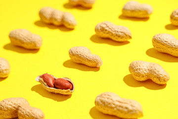 Many unpeeled peanuts on yellow background, closeup